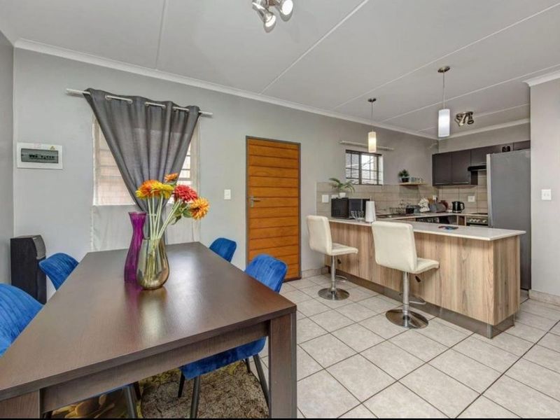 Open-plan living and dining area featuring a modern kitchen with a breakfast bar, tiled flooring, and neutral wall finishes.
