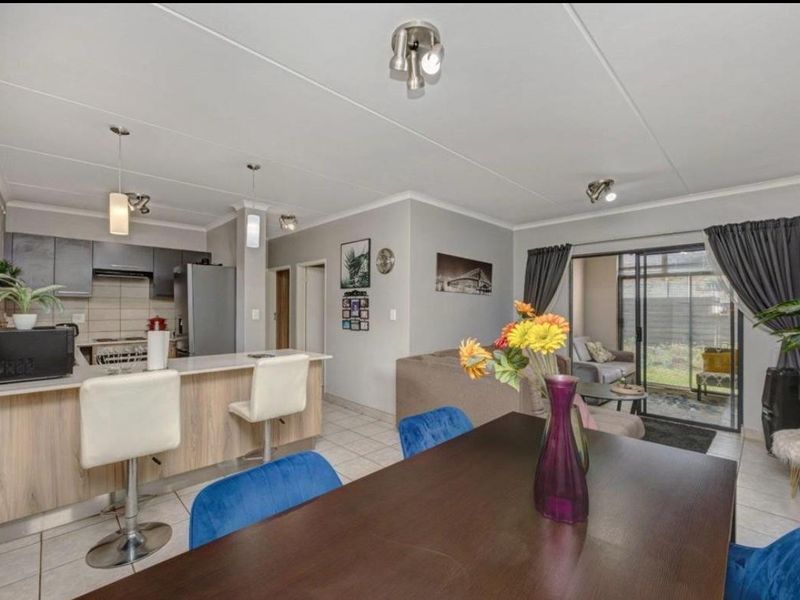 Open-plan living and dining area featuring a modern kitchen with island, tiled floors, and sliding door access to the patio.