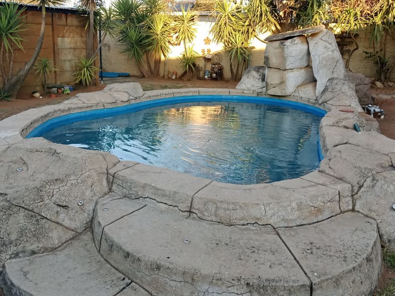 A backyard swimming pool featuring a decorative rock surround and integrated water feature.