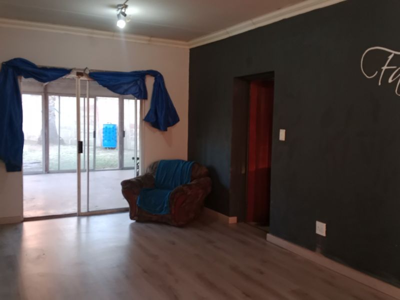 Living room featuring laminate flooring, a sliding glass door leading to the exterior, and a dark accent wall.