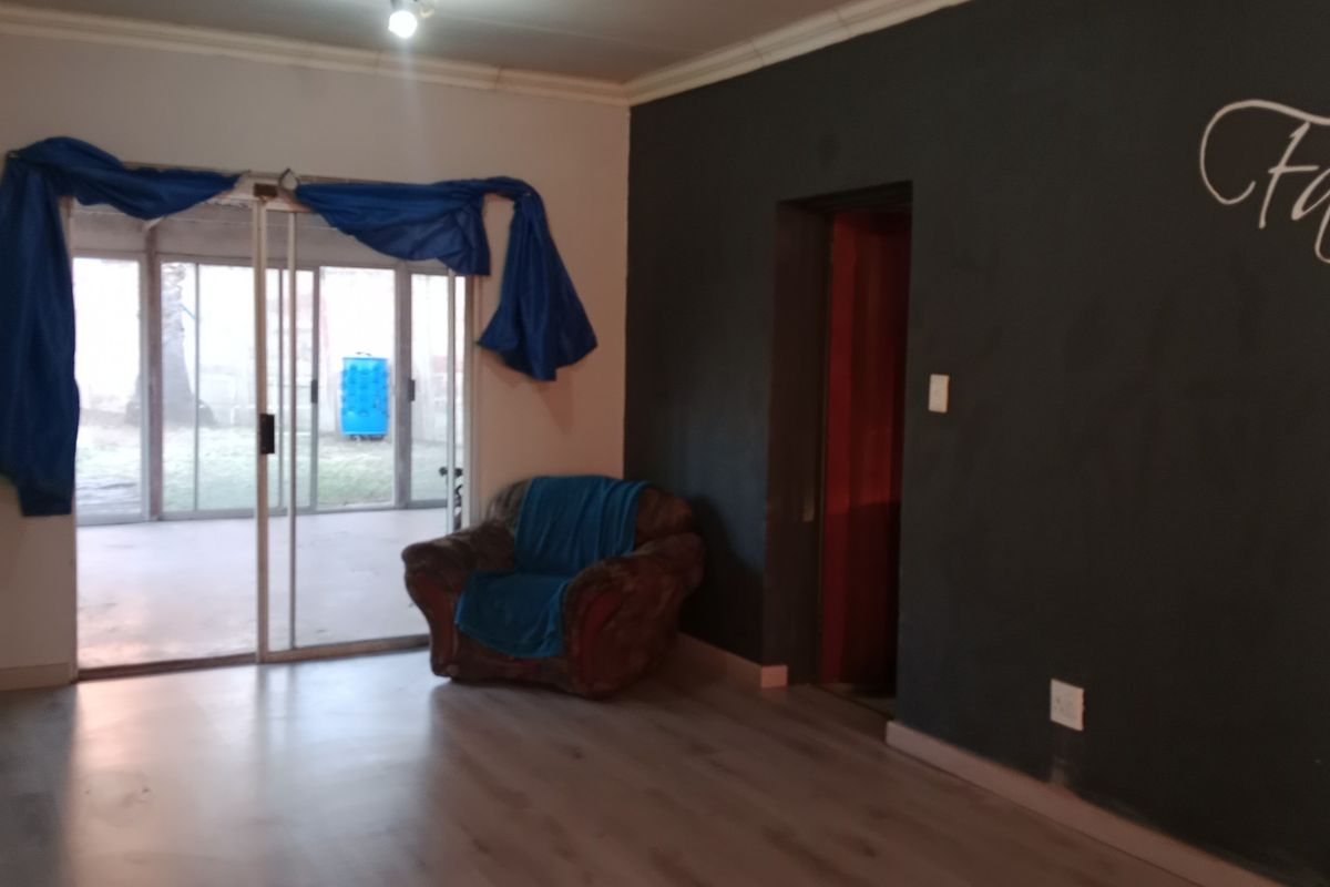 Living room featuring laminate flooring, a sliding glass door leading to the exterior, and a dark accent wall.