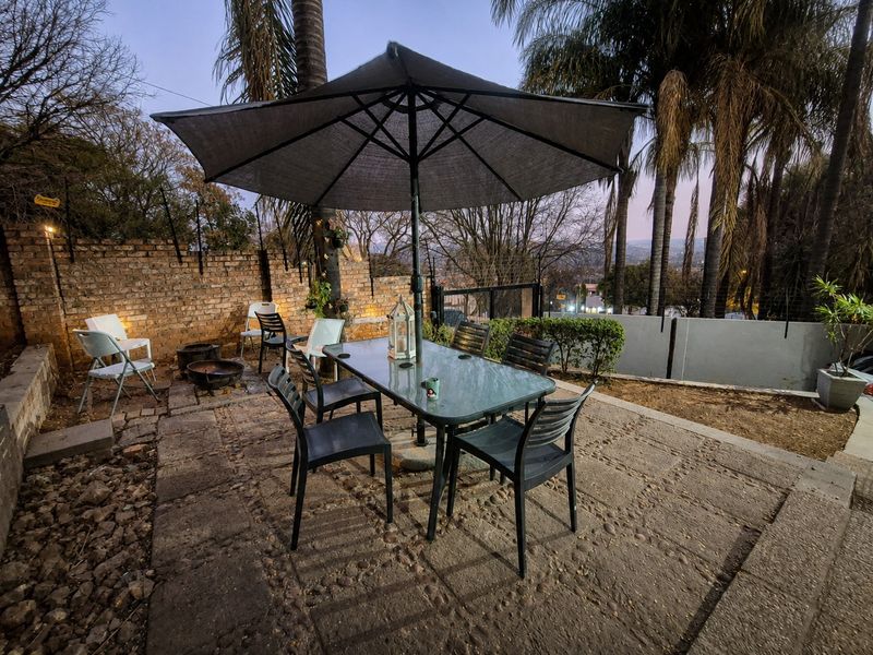 Outdoor patio area featuring stone paving and an exposed brick boundary wall, providing a functional space for outdoor dining and relaxation.