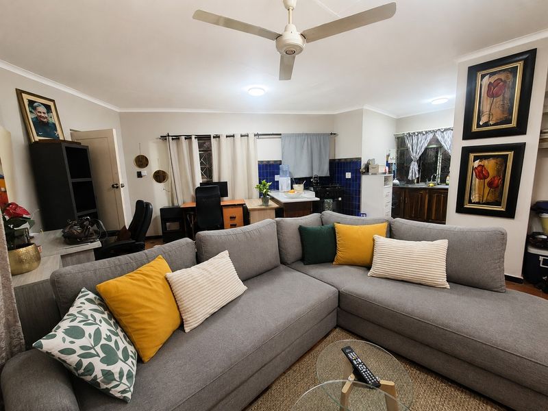 Open-plan living area featuring a combined lounge and kitchen space with ceiling fan, recessed lighting, and functional kitchen cabinetry.