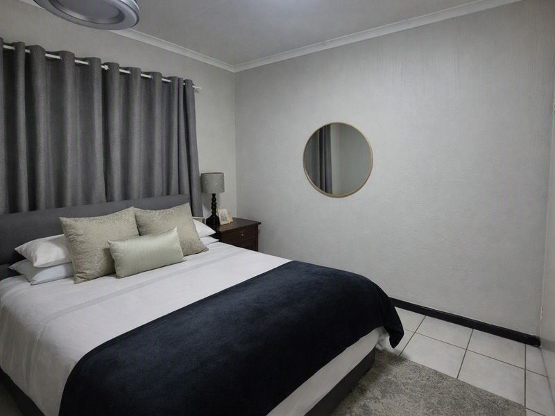 A well-maintained bedroom featuring neutral walls, tiled flooring, and built-in storage cupboards.