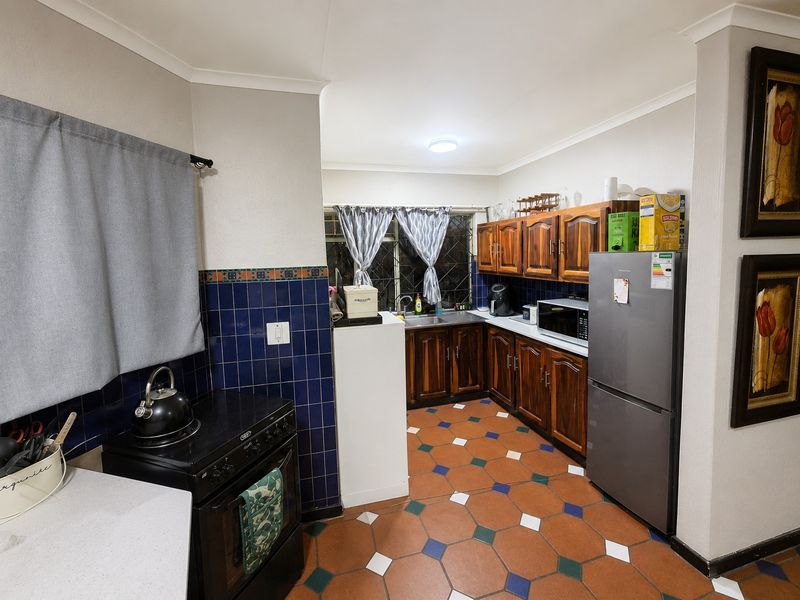 A functional kitchen featuring wooden cabinetry, a tiled backsplash, and patterned ceramic floor tiles, providing a classic cottage-style aesthetic.