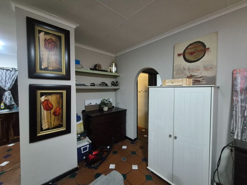 A functional hallway area featuring traditional terracotta-style tiled flooring, an arched doorway leading to an adjacent room, and built-in wall shelving.