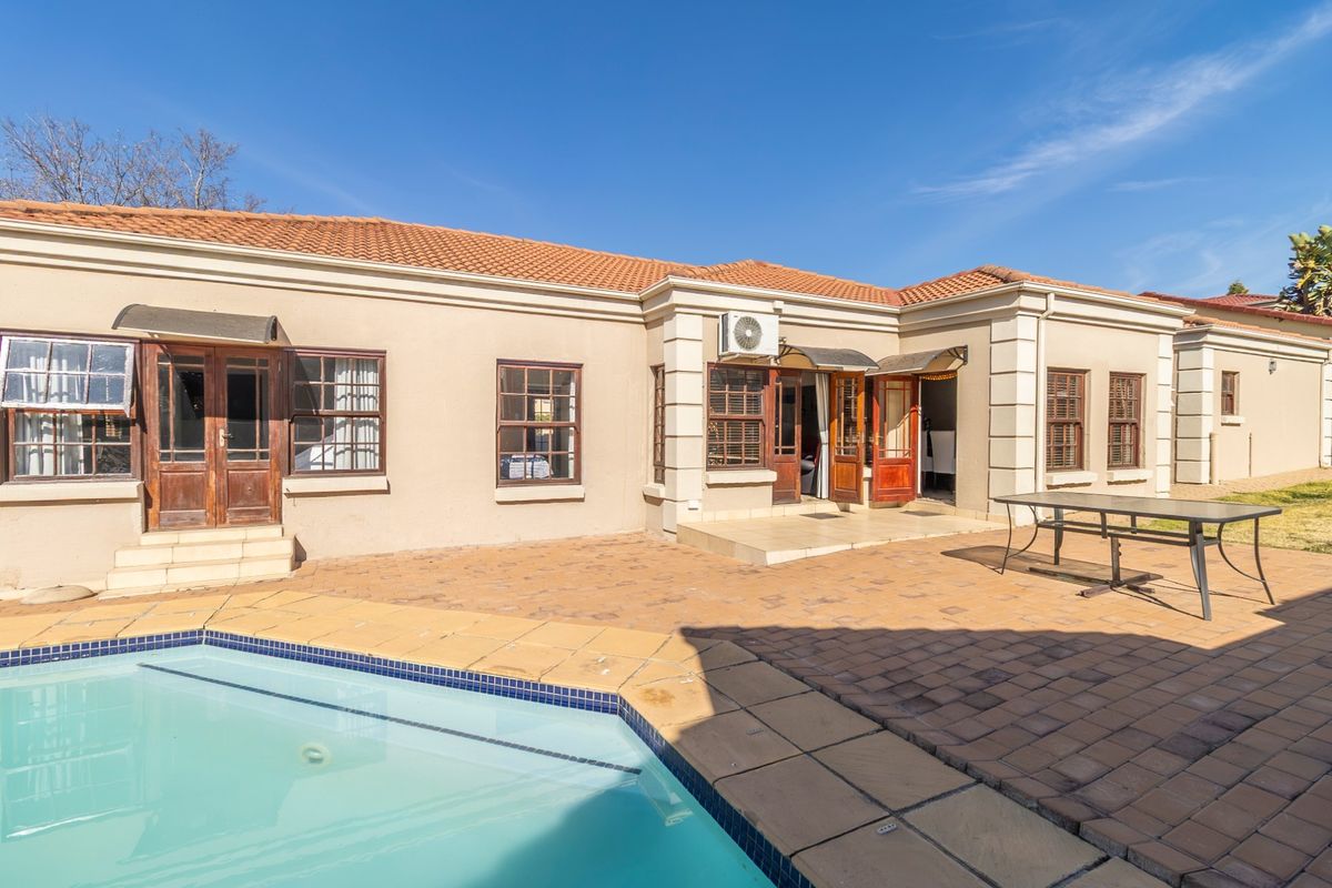 Rear exterior view featuring a swimming pool, paved patio area, and direct access to the home through multiple timber-framed doors.