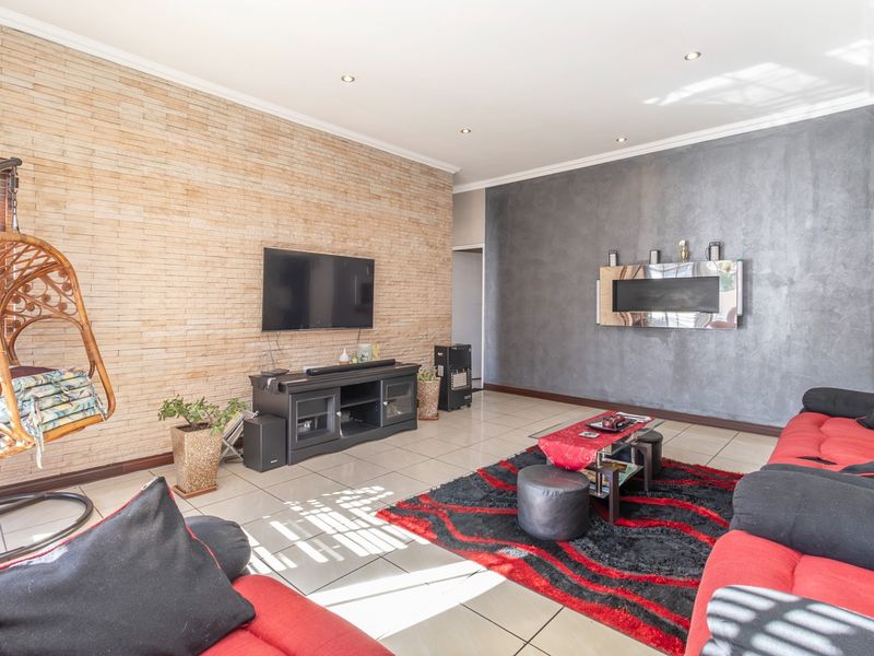 Spacious living room featuring a textured stacked stone accent wall, a modern built-in fireplace, tiled flooring, and recessed downlighting.