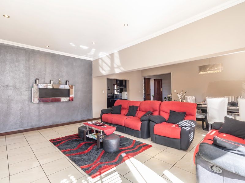 Spacious open-plan living and dining area featuring tiled floors, recessed lighting, and a modern textured feature wall.