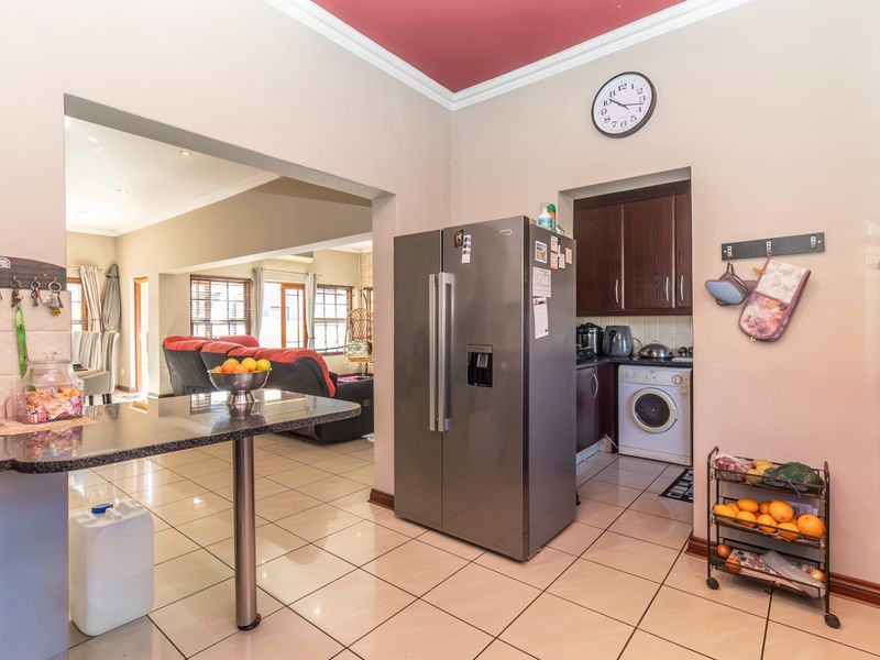 Open plan kitchen and living area featuring tiled flooring, granite countertops, and built-in cabinetry with an integrated oven and scullery area.