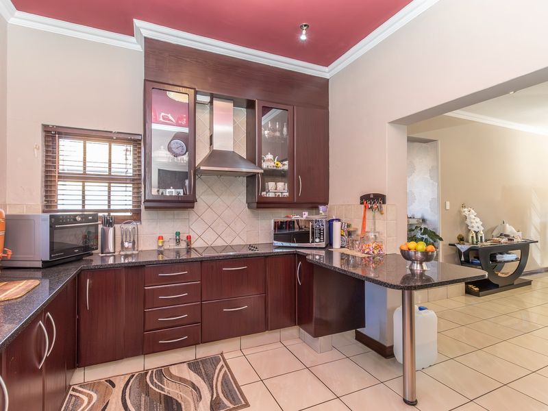 Functional kitchen featuring dark wood cabinetry, granite countertops, a breakfast bar, and a tiled backsplash, with an open-plan flow to the adjacent living area.