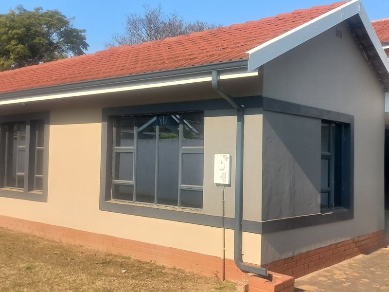 Rear view of the house featuring a terracotta tiled roof, modern grey-trimmed aluminium windows, and a well-maintained exterior facade.
