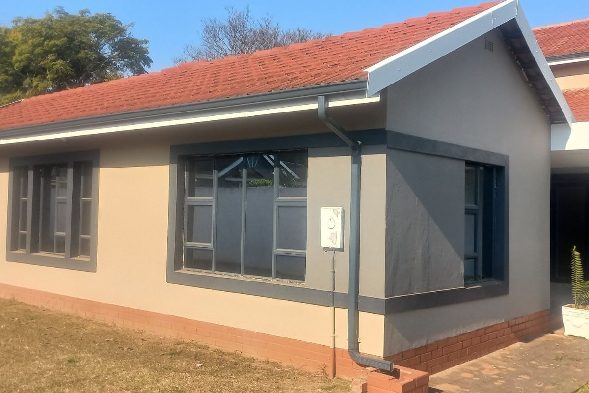 Rear view of the house featuring a terracotta tiled roof, modern grey-trimmed aluminium windows, and a well-maintained exterior facade.