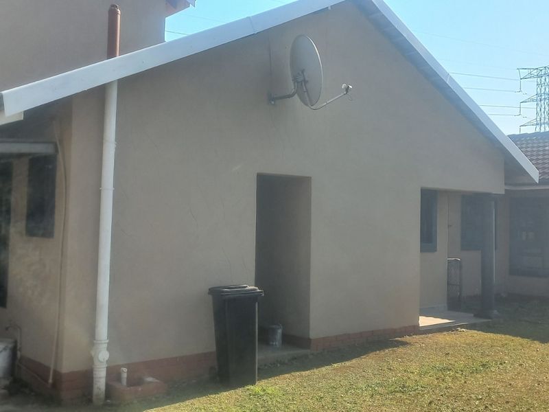 Rear view of the house featuring a tiled roof, exterior wall finish, rainwater tank, and a covered patio area.