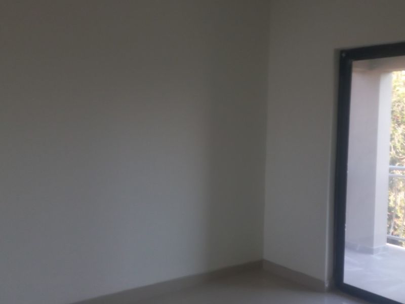 An empty bedroom featuring tiled flooring and a large sliding glass door providing access to an outdoor balcony area.