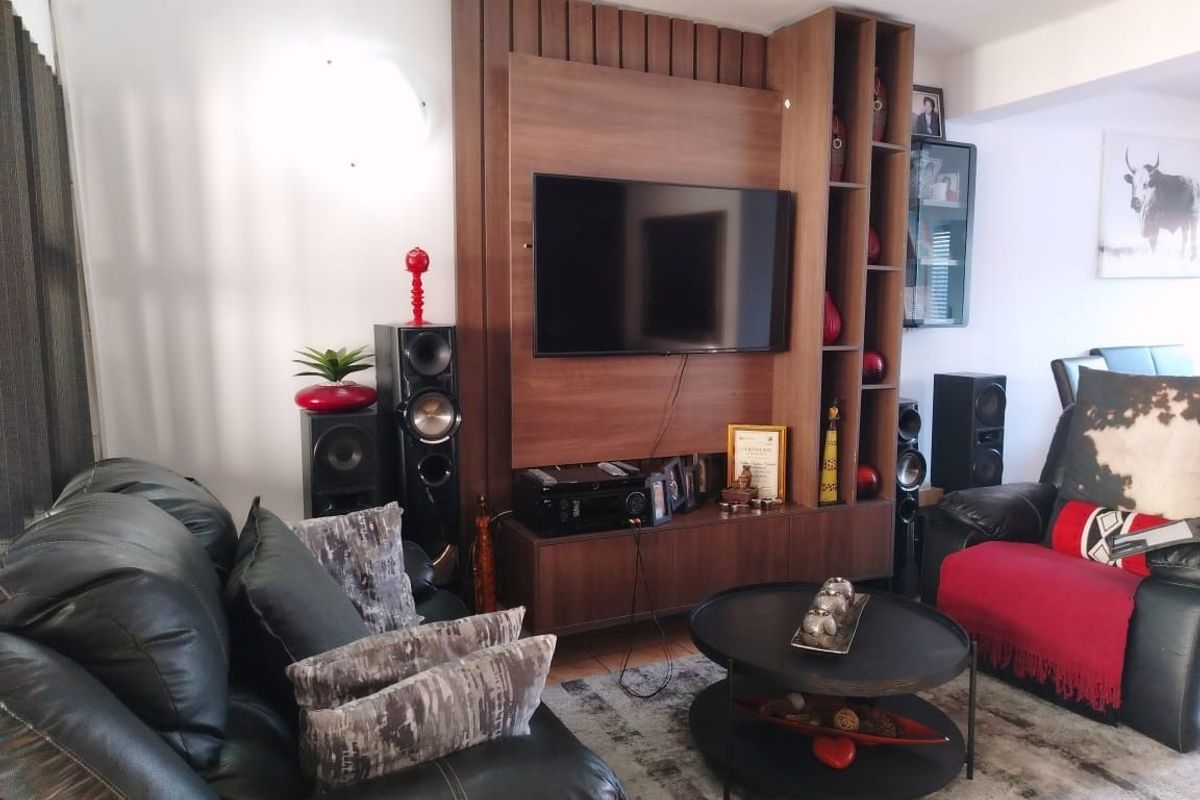 A comfortable living room featuring a custom-built timber media wall unit with integrated shelving and cabinetry.