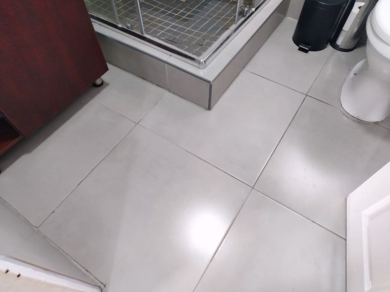 A functional bathroom featuring tiled flooring, a shower enclosure, and a standard toilet fixture.