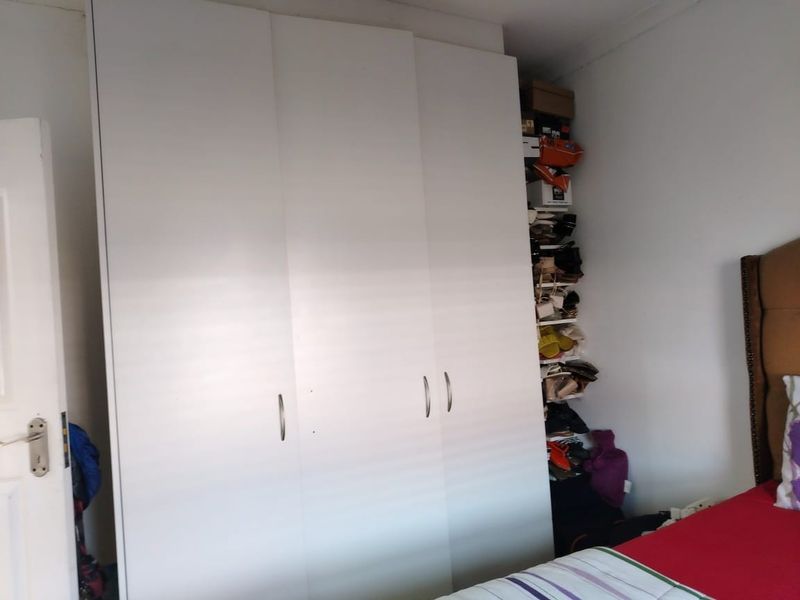 A bedroom featuring a large white built-in wardrobe with modern handles, providing ample storage space.