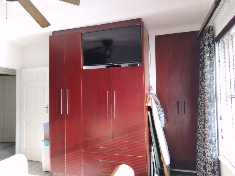 Bedroom featuring dark wood built-in cupboards with integrated storage and a ceiling fan.