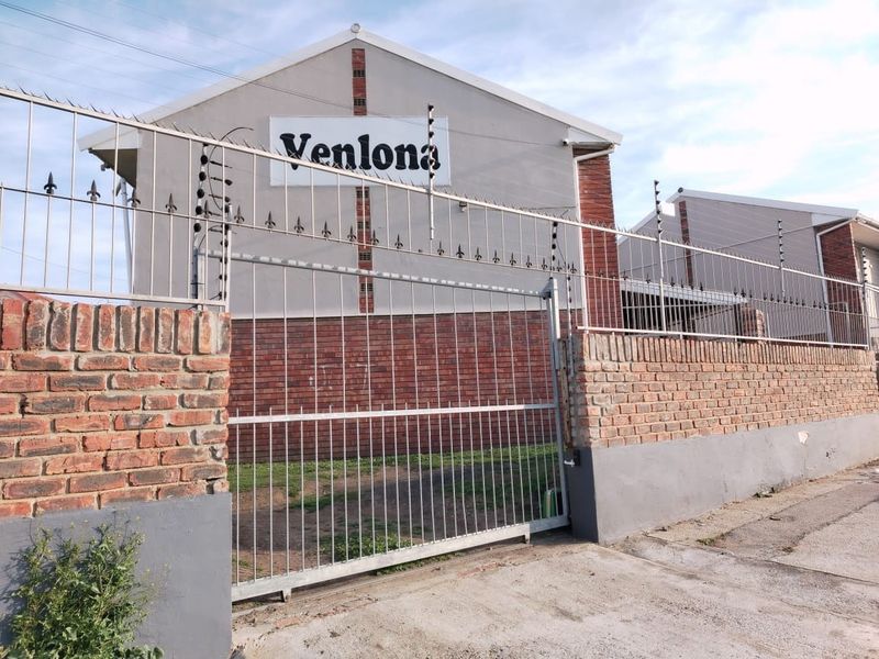 Front exterior view of the property featuring a secure gated entrance with electric fencing and a brick boundary wall.