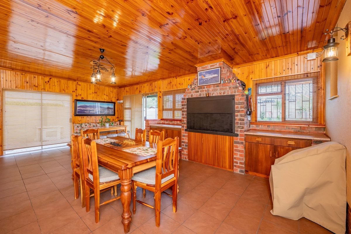 Spacious living area featuring extensive pine wood paneling, a built-in brick fireplace, tiled flooring, and direct access to the outdoors via sliding glass doors.