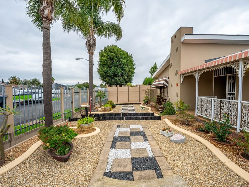 Front exterior view featuring a landscaped gravel garden, decorative paved walkway, and a covered veranda with ornate wrought iron detailing.
