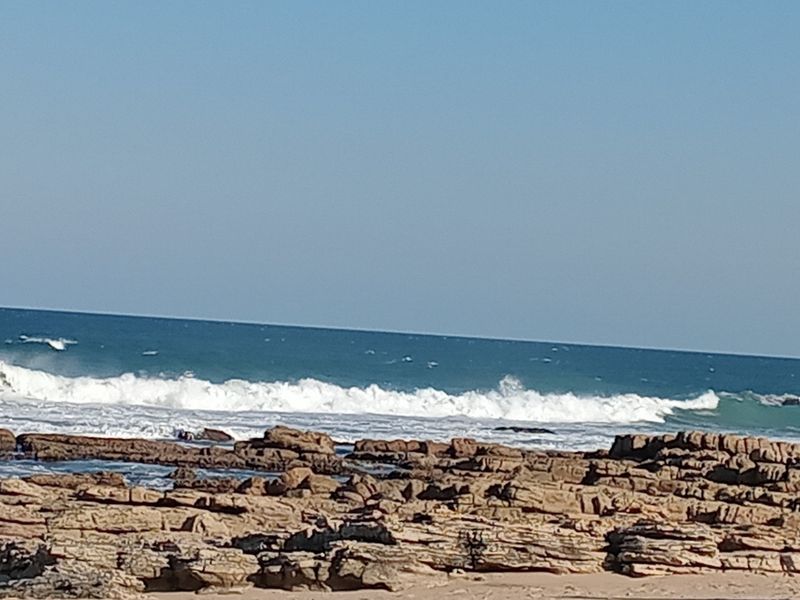 A scenic view of the ocean coastline featuring rocky formations and crashing waves.