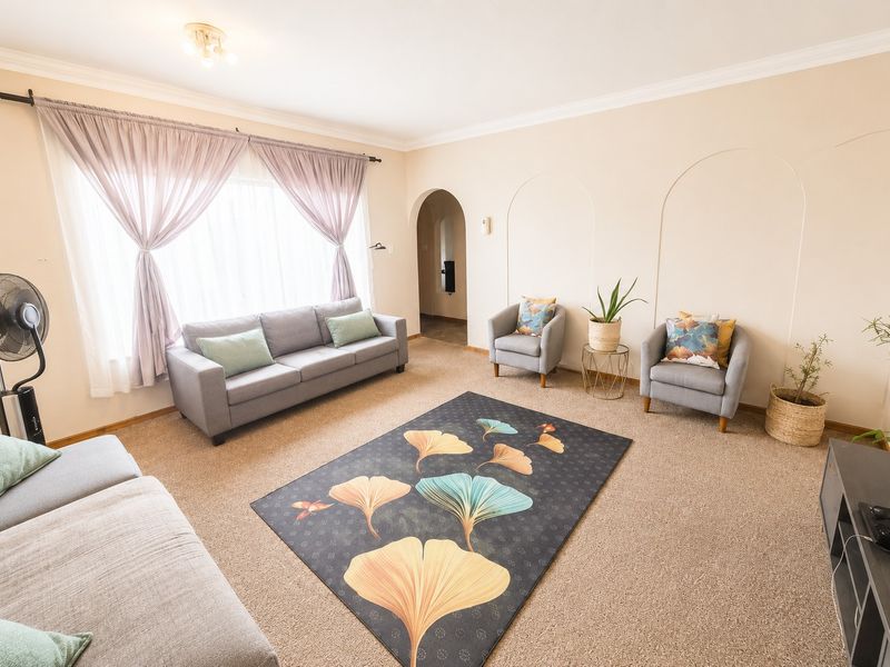 A comfortable living room featuring carpeted flooring, decorative wall arch detailing, and an arched doorway leading to adjacent spaces.