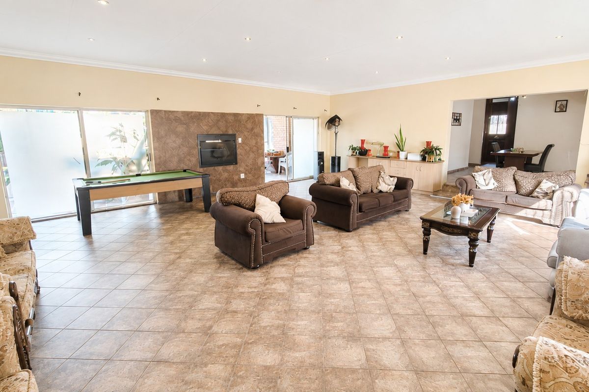 Spacious living room featuring tiled flooring, recessed lighting, and a built-in fireplace with direct access to the outdoor area through sliding glass doors.