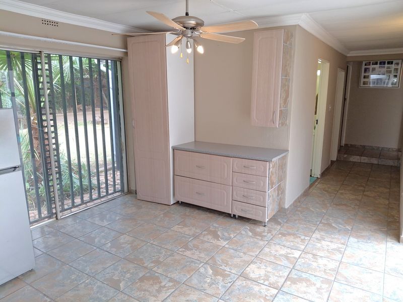 A living area featuring tiled flooring, a ceiling fan, and built-in cabinetry, with direct access to the garden through a sliding glass door.
