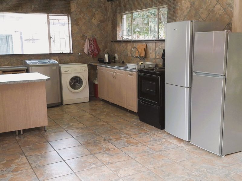A functional kitchen featuring laminate cabinetry, stone-look tiled finishes, and integrated appliance connections, providing a practical workspace with direct access to the exterior.