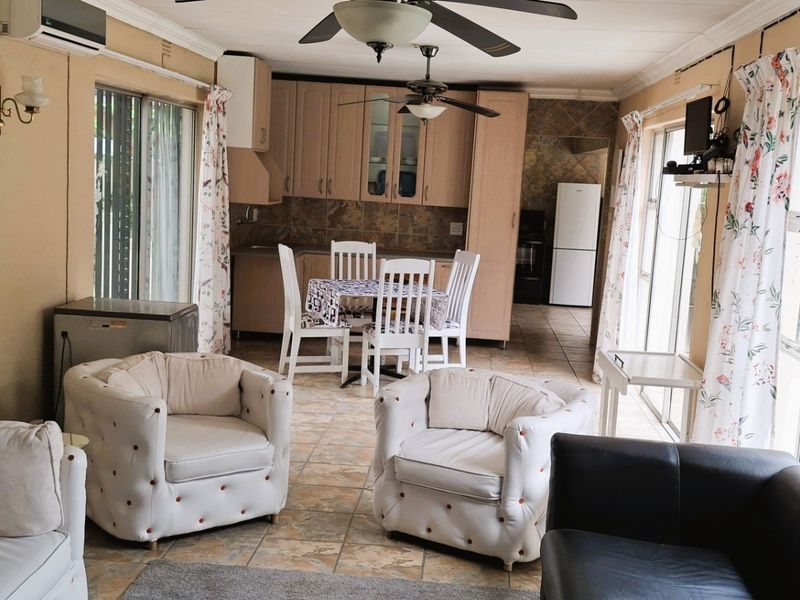 Open-plan living and dining area featuring tiled floors, ceiling fans, and direct access to the outdoors through sliding glass doors.