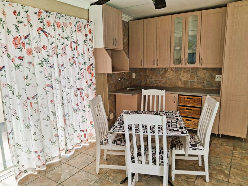 A functional kitchen featuring laminate cabinetry, stone-look tile backsplash, and tiled flooring, providing a practical workspace with integrated storage solutions.