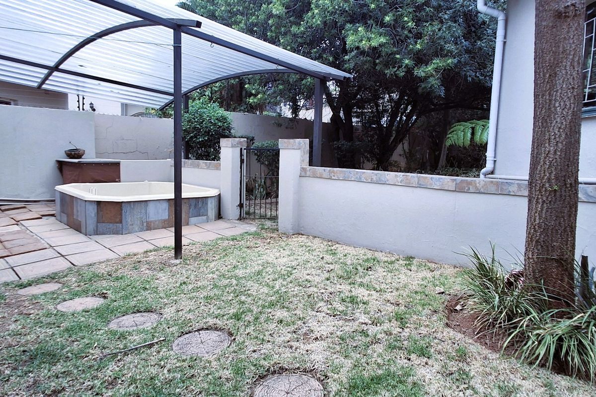 Rear garden area featuring a built-in spa, covered patio structure, and boundary walling, offering potential for outdoor entertainment space enhancement.