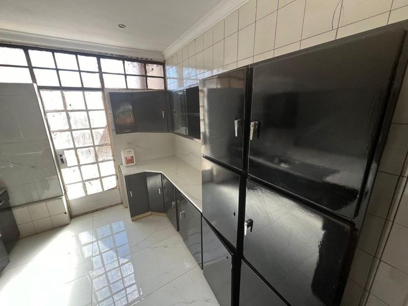 A dated kitchen featuring dark built-in cabinetry, white tiled flooring, and a glass panel door leading to the exterior.
