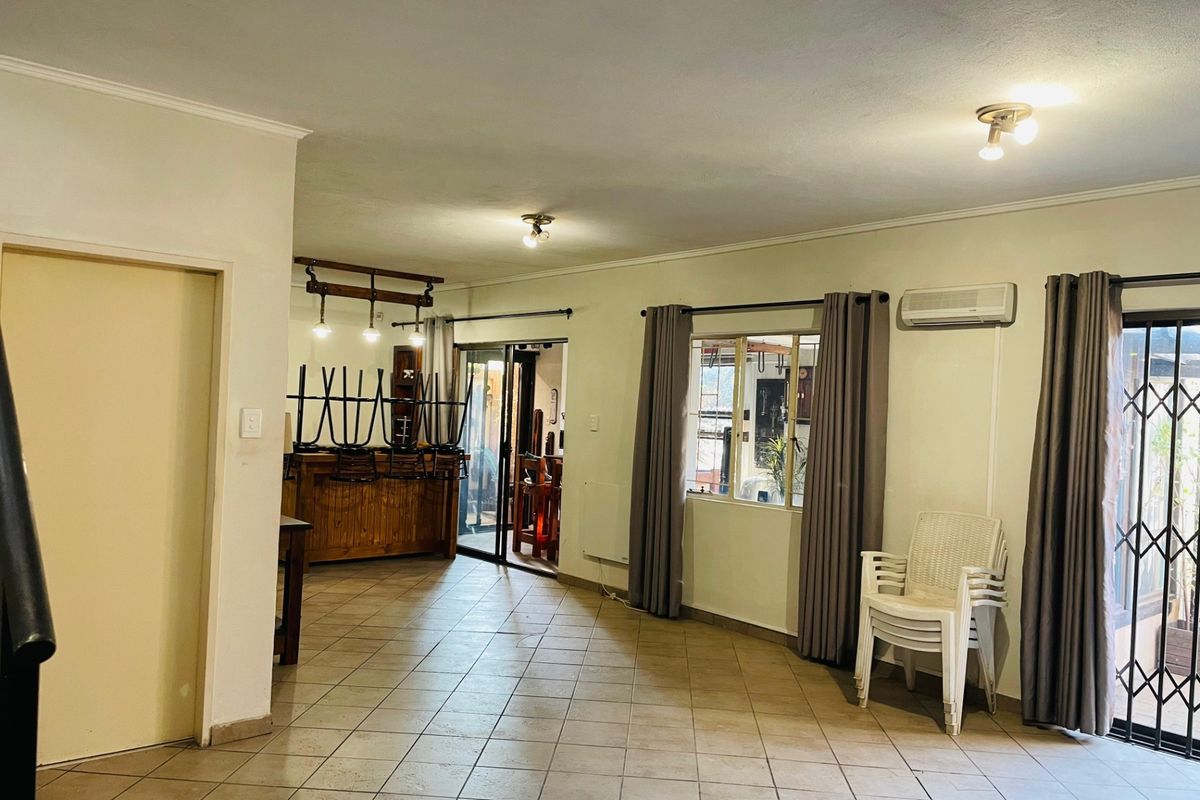 Spacious living area featuring tiled flooring, an air conditioning unit, and a built-in bar counter, with direct access to the outdoor area via sliding doors.