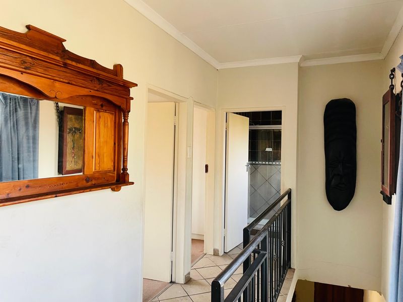 A functional hallway featuring tiled flooring and a metal balustrade, providing access to adjacent rooms and a bathroom.