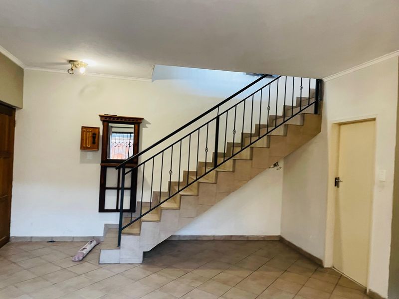 A spacious hallway featuring a tiled staircase with a wrought iron balustrade, providing a clean and functional transition area within the home.