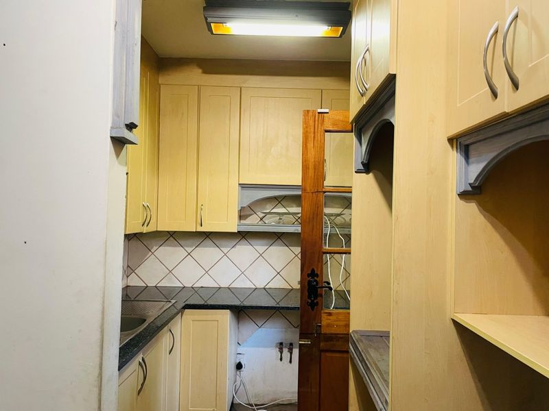 A compact kitchen featuring light wood cabinetry, granite countertops, and a tiled backsplash, currently vacant and ready for updates.