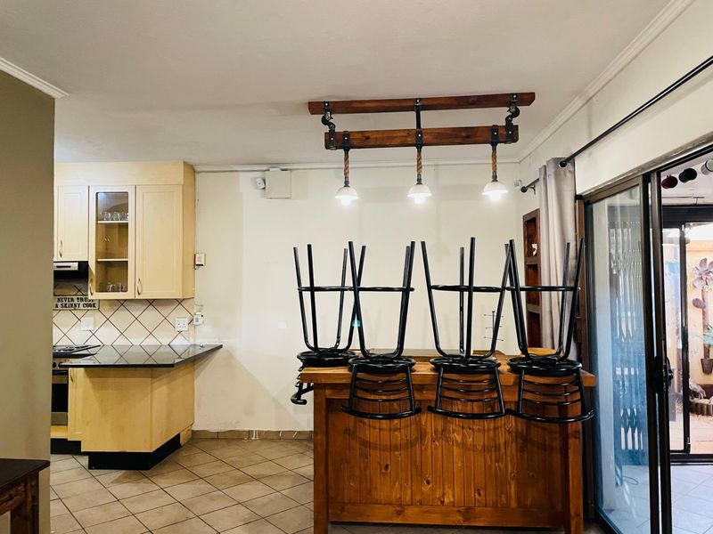 Kitchen area featuring built-in cabinetry, granite countertops, integrated appliances, and a breakfast bar with pendant lighting, leading to an outdoor patio area.
