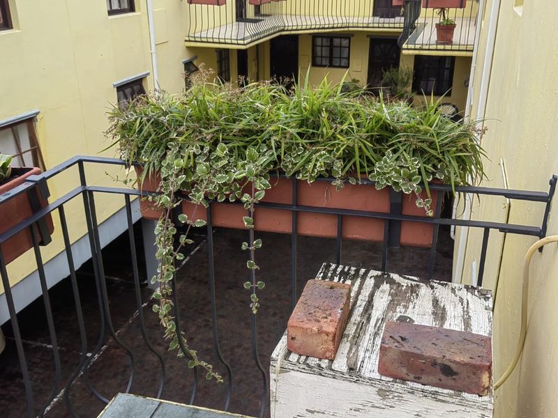 A balcony overlooking an internal courtyard, featuring metal railings and tiled flooring, providing an outdoor space for the apartment.