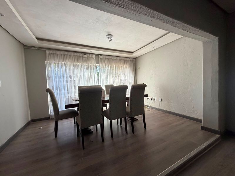 Dining room featuring laminate flooring and a recessed ceiling, providing a functional space for family meals.