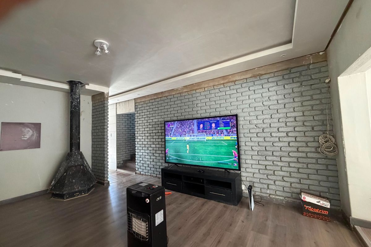 Living room featuring an exposed brick wall, laminate flooring, and a freestanding fireplace, currently requiring some finishing touches to the wall edges and trim.