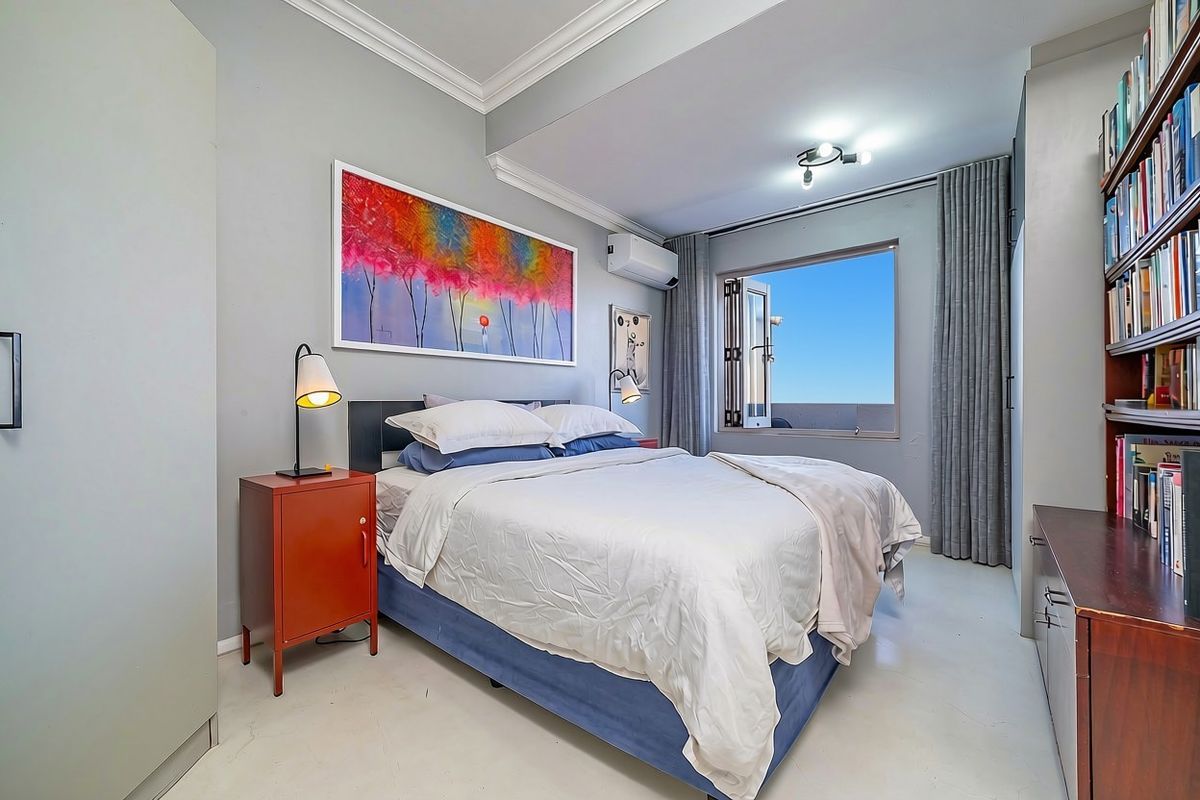 A well-maintained bedroom featuring crown molding, an air conditioning unit, and a casement window with access to an outdoor area.