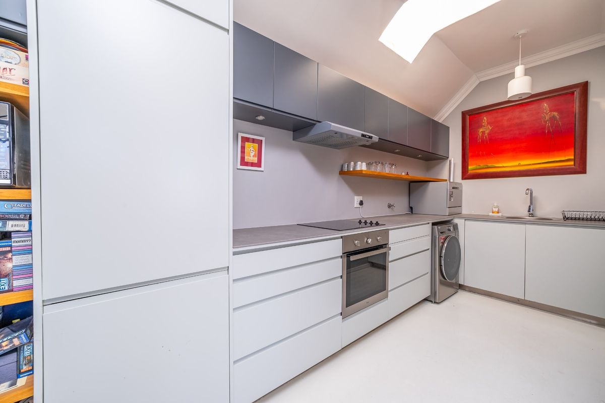 Modern kitchen featuring sleek grey cabinetry, integrated appliances, electric hob, built-in oven, and a stainless steel sink with a clean, minimalist aesthetic.