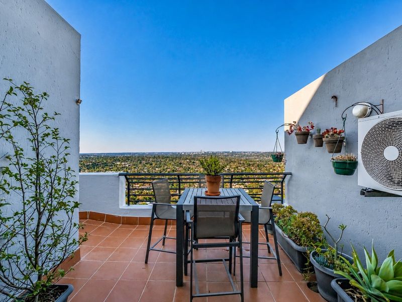 A private balcony featuring tiled flooring, a metal balustrade, and an elevated view of the surrounding landscape.