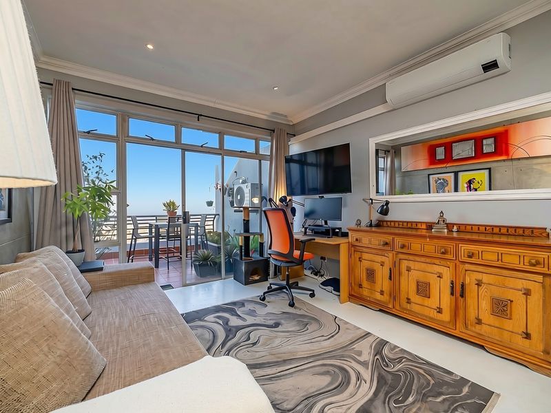 A well-maintained living room featuring a concrete accent wall, split-system air conditioning, and large sliding glass doors providing access to an outdoor balcony.