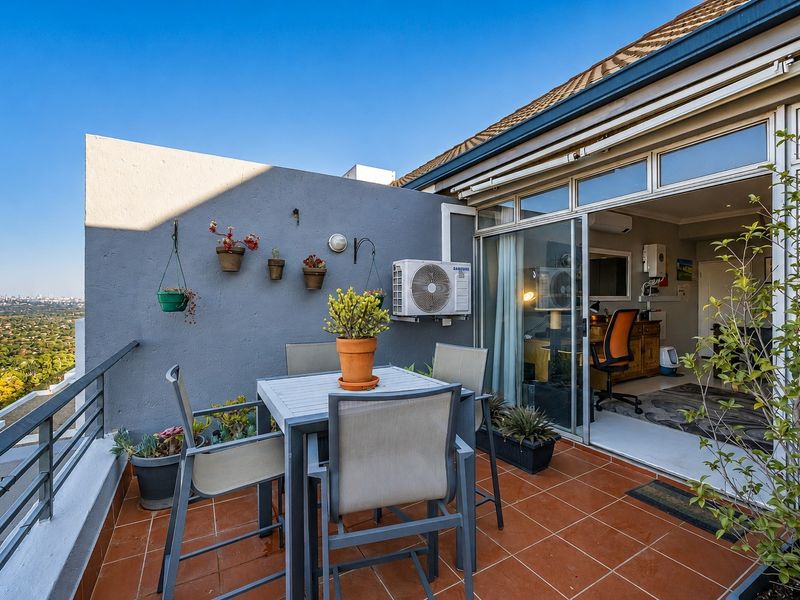 A spacious balcony featuring tiled flooring, a metal balustrade, and sliding glass doors providing seamless access to the interior living space.