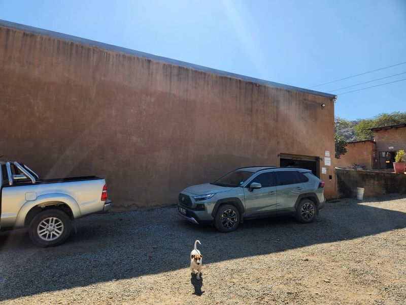 Rear exterior view of the farm property featuring a large plastered masonry wall and a gravel driveway area.