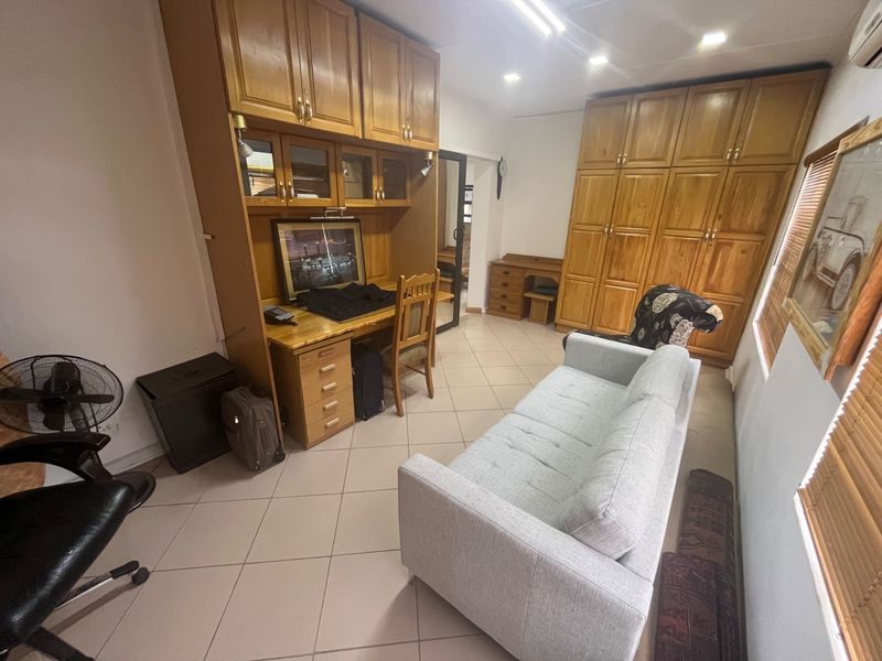 A bedroom featuring extensive built-in wooden cabinetry, a integrated desk workspace, tiled flooring, and recessed ceiling lighting.